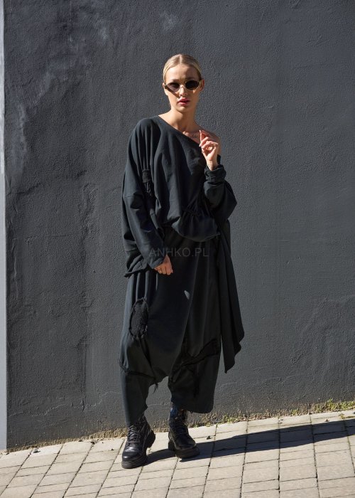 Czarne spodnie damskie oversize z obniżonym krokiem i ozdobnymi aplikacjami, zestawione z botkami i luźną bluzą w nowoczesnej stylizacji streetwear.