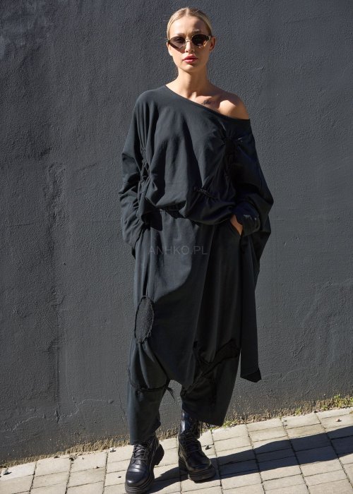 Czarne spodnie damskie oversize z obniżonym krokiem i ozdobnymi aplikacjami, zestawione z botkami i luźną bluzą w nowoczesnej stylizacji streetwear.