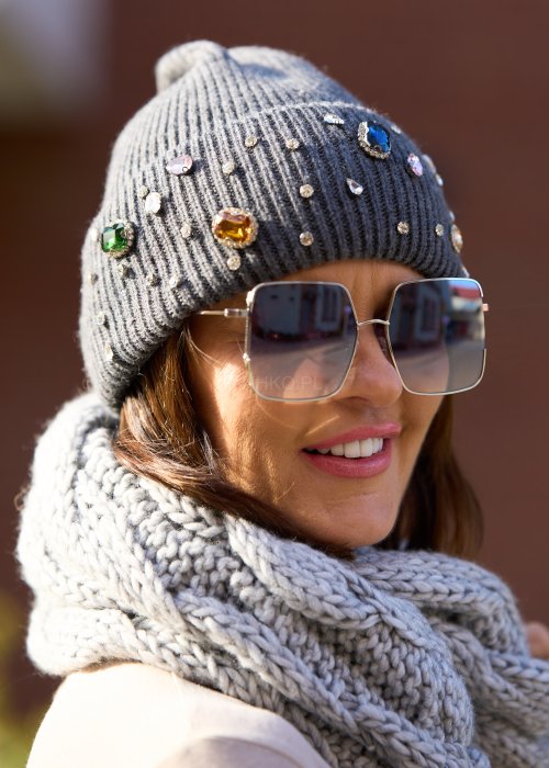 szarej czapce z dużymi kolorowymi kryształkami