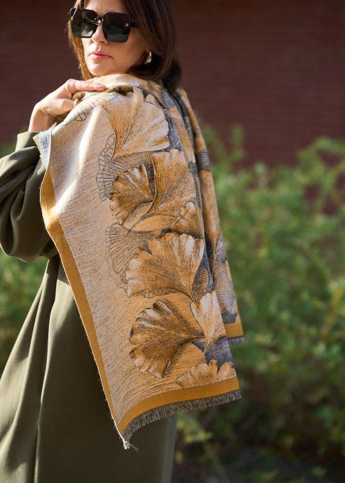 dużą szalikopłachtą we wzór liści w odcieniach złota i zieleni