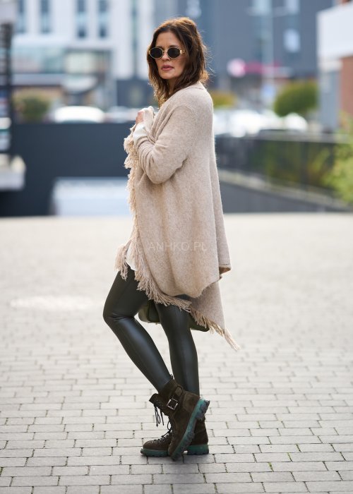 Beżowa narzutka z miękkiej dzianiny, luźny krój oversize i długie frędzle, styl boho w modzie damskiej