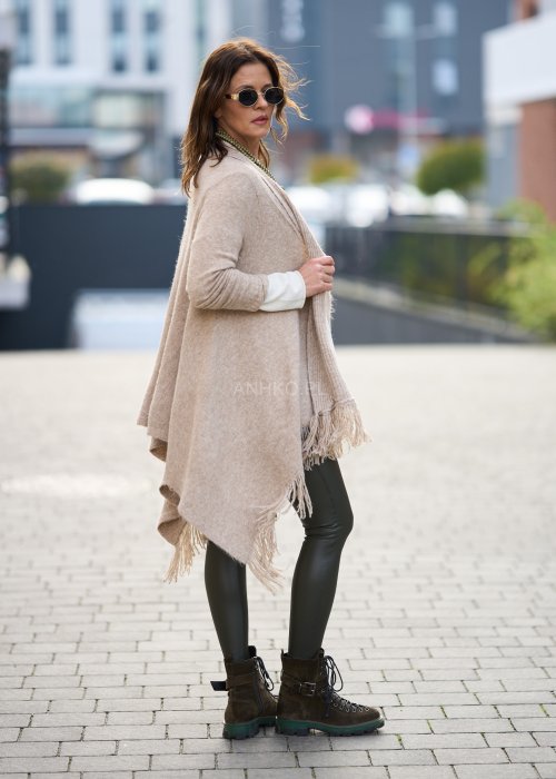 Beżowa narzutka z miękkiej dzianiny, luźny krój oversize i długie frędzle, styl boho w modzie damskiej