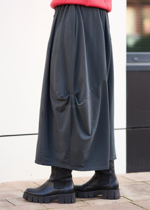 Antracytowa spódnica maxi typu bombka z elastycznym pasem i przeszyciami, zestawiona z czerwonym swetrem i czarnymi botkami w miejskiej stylizacji.