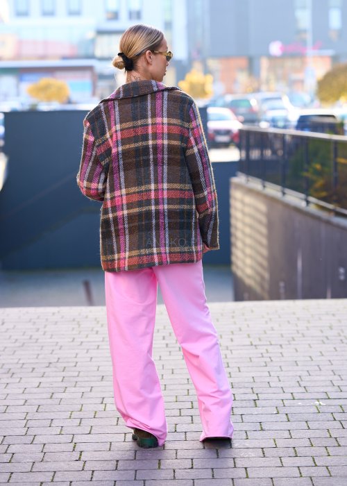 Różowe spodnie dresowe damskie z elastyczną talią i sznurkiem, o luźnym kroju i długich nogawkach, stylizowane w miejskim casualowym looku ze sneakersami.