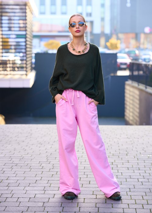 Różowe spodnie dresowe damskie z elastyczną talią i sznurkiem, o luźnym kroju i długich nogawkach, stylizowane w miejskim casualowym looku ze sneakersami.