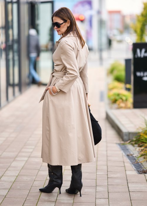 Damska beżowa sukienka midi z wiązaniem w talii i dekoltem V, zapinana na guziki do połowy. Model o luźnym kroju i eleganckiej, minimalistycznej formie.