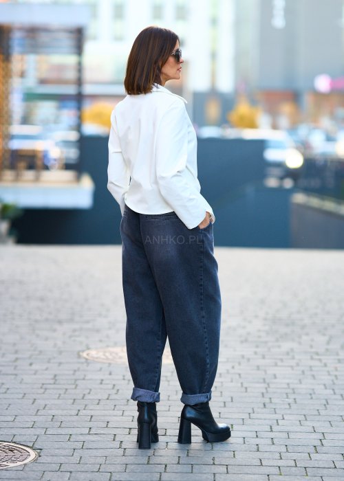Biała koszula damska z asymetrycznym wiązaniem i klasycznym kołnierzem. Stylizacja z ciemnymi spodniami i biżuterią w eleganckim, miejskim stylu.