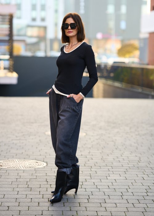 Antracytowe jeansy damskie o luźnym kroju z podwiniętymi nogawkami, stylizowane z czarnym topem i botkami na obcasie w miejskim looku.