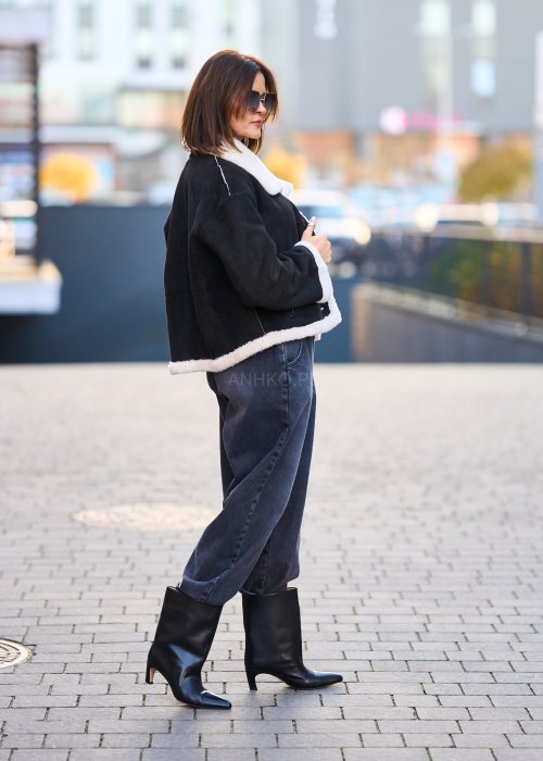 Antracytowe jeansy damskie o luźnym kroju z podwiniętymi nogawkami, stylizowane z czarnym topem i botkami na obcasie w miejskim looku.