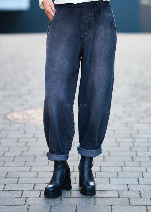 Antracytowe jeansy damskie o luźnym kroju z podwiniętymi nogawkami, stylizowane z czarnym topem i botkami na obcasie w miejskim looku.