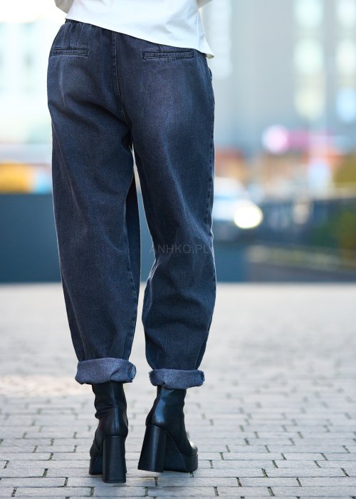 Antracytowe jeansy damskie o luźnym kroju z podwiniętymi nogawkami, stylizowane z czarnym topem i botkami na obcasie w miejskim looku.