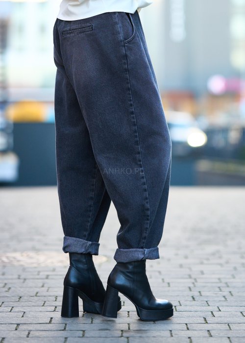 Antracytowe jeansy damskie o luźnym kroju z podwiniętymi nogawkami, stylizowane z czarnym topem i botkami na obcasie w miejskim looku.