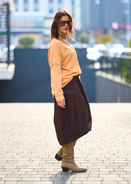 Kobieta w pomarańczowej bluzce z dekoltem w serek i brązowej spódnicy, casualowa stylizacja w ciepłych jesiennych kolorach