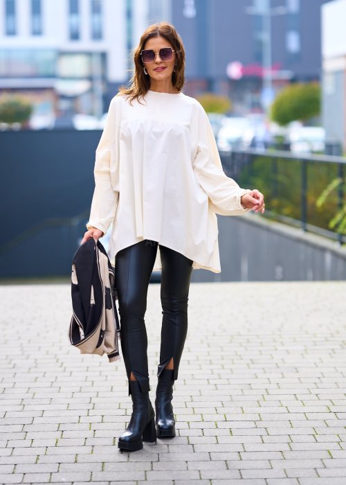 Kobieta w oversize kremowej bluzce z długim rękawem i legginsach ze skóry ekologicznej, minimalistyczna stylizacja w miejskim stylu