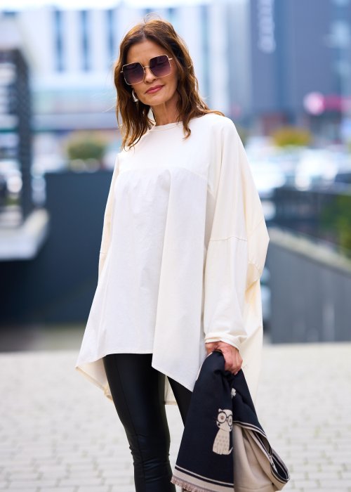 Kobieta w oversize kremowej bluzce z długim rękawem i legginsach ze skóry ekologicznej, minimalistyczna stylizacja w miejskim stylu