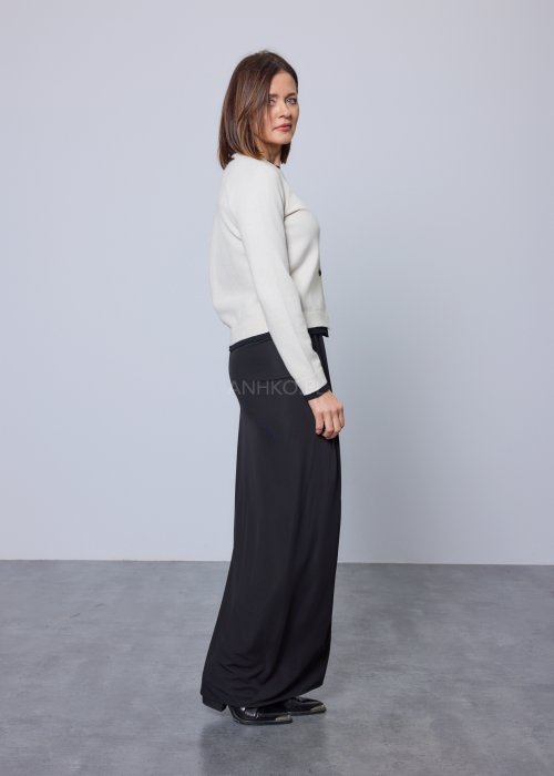 Jasnobeżowy kardigan zapinany na czarne guziki, z czarnymi lamówkami przy kołnierzu, mankietach i dole