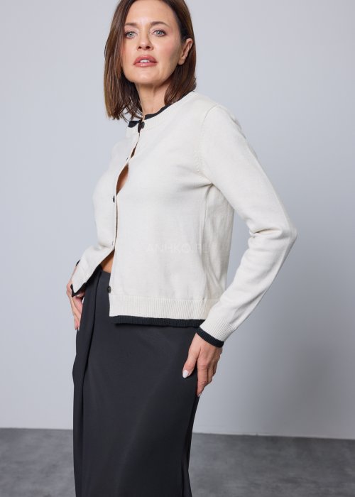 Jasnobeżowy kardigan zapinany na czarne guziki, z czarnymi lamówkami przy kołnierzu, mankietach i dole