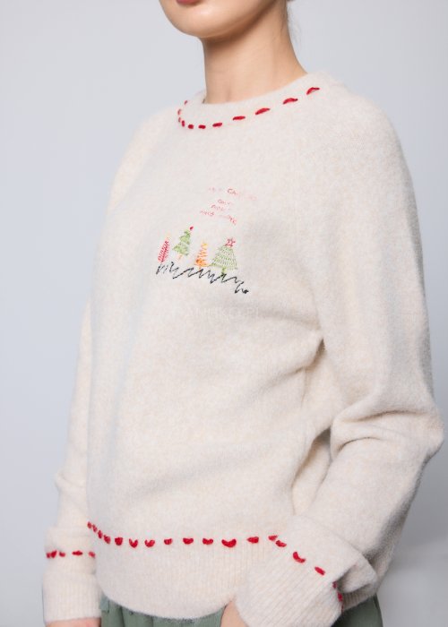 Kremowy, miękki sweter z czerwonymi przeszyciami i świątecznym haftem choinek