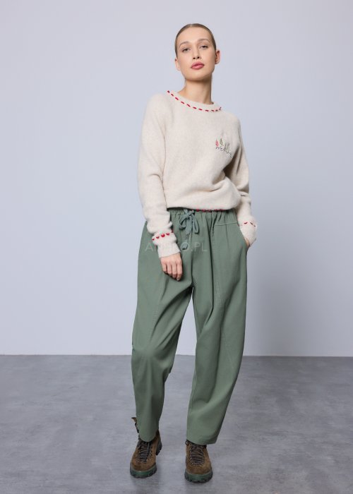 Kremowy, miękki sweter z czerwonymi przeszyciami i świątecznym haftem choinek