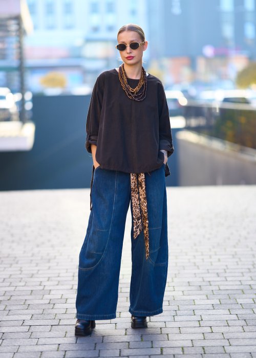 Bluzka oversize w kolorze głębokiego brązu z długim rękawem i regulowanym dołem na troczki, zestawiona z jeansami w miejskiej stylizacji