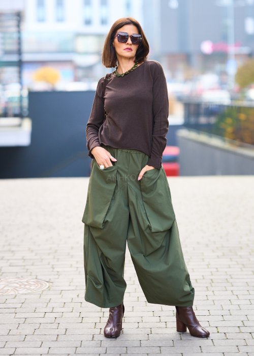 Zielone spodnie o szerokich nogawkach z dużymi kieszeniami cargo z przodu, zakończone zwężanym dołem