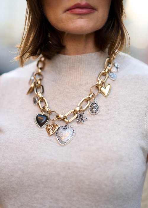 Złoty naszyjnik z dużymi ogniwami i zawieszkami w kształcie serc oraz medalionów. Efektowna biżuteria damska podkreślająca szyję i uzupełniająca elegancką stylizację.