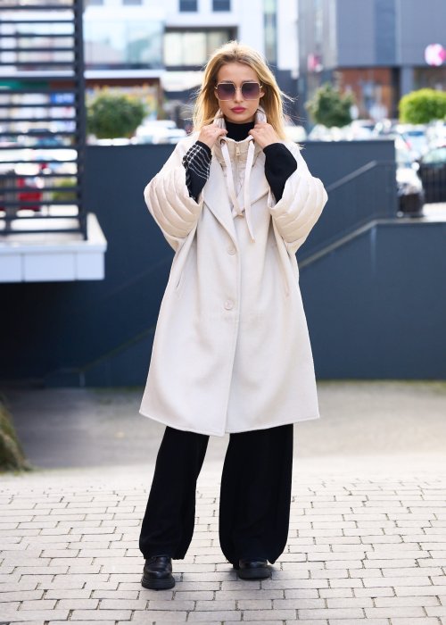 Elegancki płaszcz damski w kolorze ecru z pikowanymi rękawami, długim krojem i klasycznym kołnierzem oversize