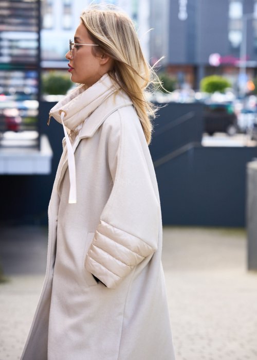 Elegancki płaszcz damski w kolorze ecru z pikowanymi rękawami, długim krojem i klasycznym kołnierzem oversize