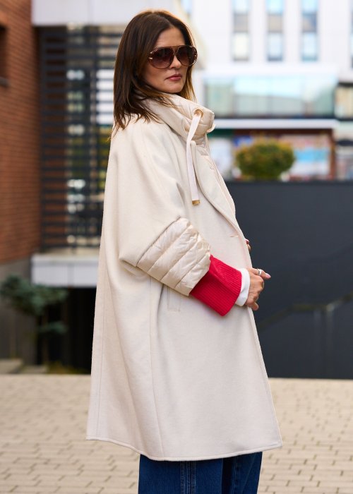 Elegancki płaszcz damski w kolorze ecru z pikowanymi rękawami, długim krojem i klasycznym kołnierzem oversize