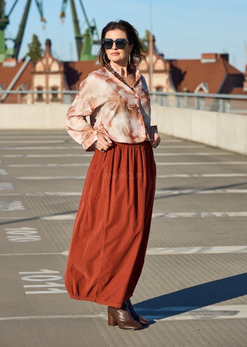 Ceglana spódnica maxi z elastyczną talią i kieszeniami, o luźnym kroju, zestawiona z brązową marynarką i skórzanymi botkami na obcasie w eleganckiej, miejskiej stylizacji.