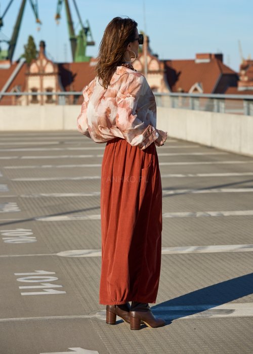 Ceglana spódnica maxi z elastyczną talią i kieszeniami, o luźnym kroju, zestawiona z brązową marynarką i skórzanymi botkami na obcasie w eleganckiej, miejskiej stylizacji.