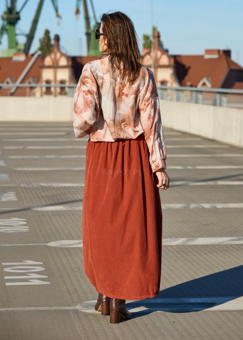 Ceglana spódnica maxi z elastyczną talią i kieszeniami, o luźnym kroju, zestawiona z brązową marynarką i skórzanymi botkami na obcasie w eleganckiej, miejskiej stylizacji.