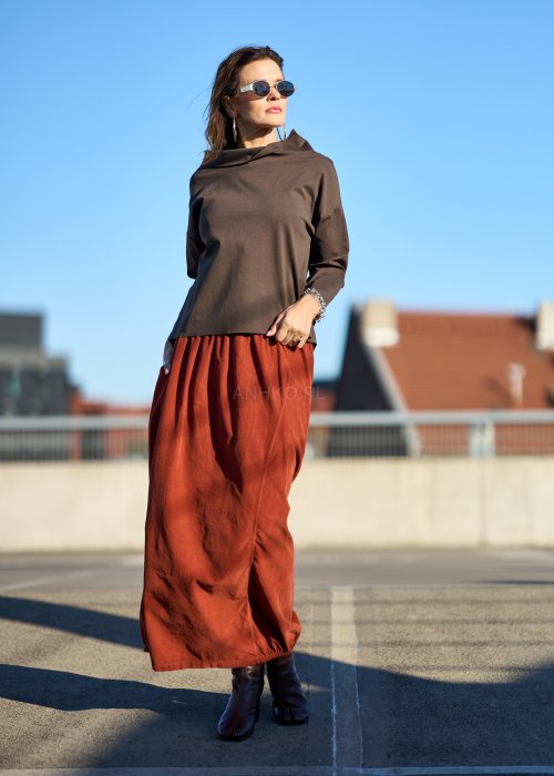 Ceglana spódnica maxi z elastyczną talią i kieszeniami, o luźnym kroju, zestawiona z brązową marynarką i skórzanymi botkami na obcasie w eleganckiej, miejskiej stylizacji.