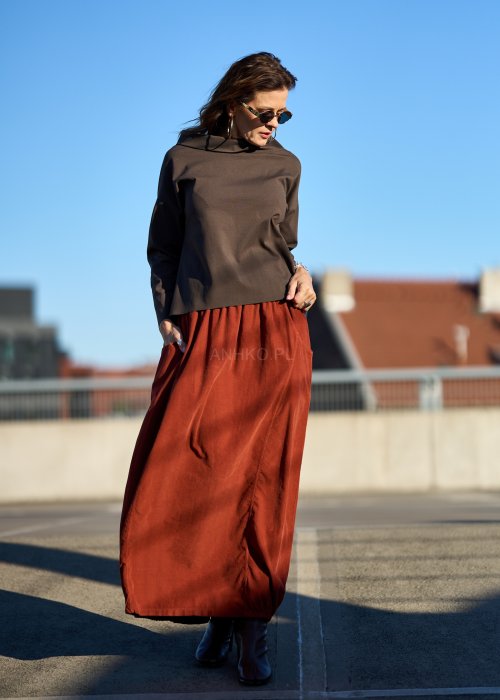 Ceglana spódnica maxi z elastyczną talią i kieszeniami, o luźnym kroju, zestawiona z brązową marynarką i skórzanymi botkami na obcasie w eleganckiej, miejskiej stylizacji.