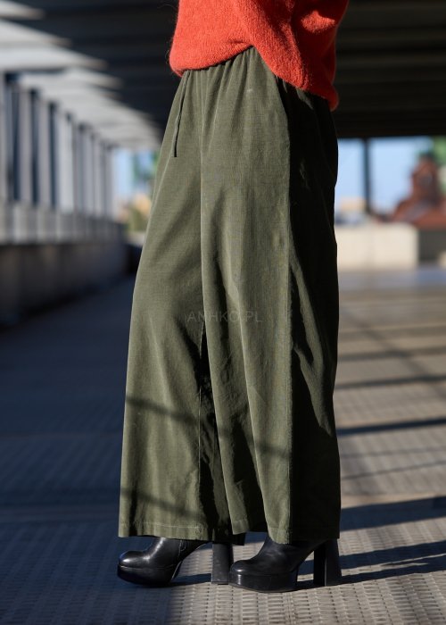 Sztruksowe spodnie damskie w kolorze khaki z szeroką nogawką i elastycznym pasem, zestawione z oversize’owym swetrem i botkami na obcasie.