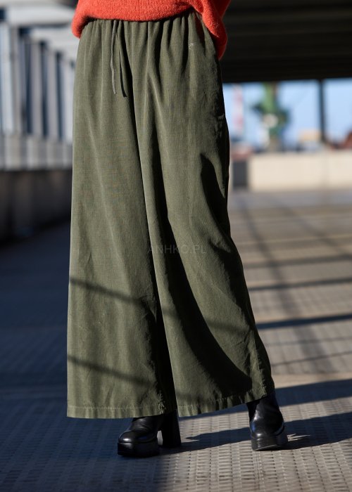 Sztruksowe spodnie damskie w kolorze khaki z szeroką nogawką i elastycznym pasem, zestawione z oversize’owym swetrem i botkami na obcasie.