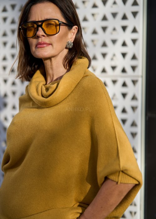 Sweter oversize w kolorze musztardowym z szerokim kołnierzem typu komin i luźnym krojem poncza. Model w stylizacji miejskiej, podkreślający miękką dzianinę i swobodny fason.
