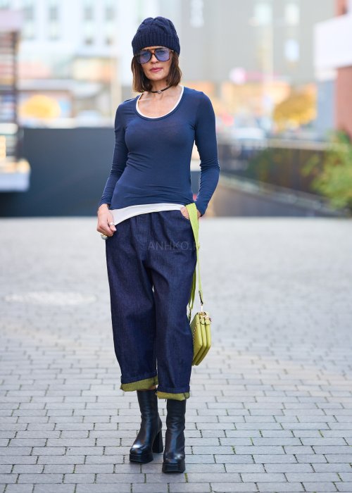 Luźne granatowe spodnie jeansowe z zielonymi detalami na kieszeni i podwiniętych nogawkach, stylizowane z dopasowaną bluzką i botkami na obcasie w miejskim looku.