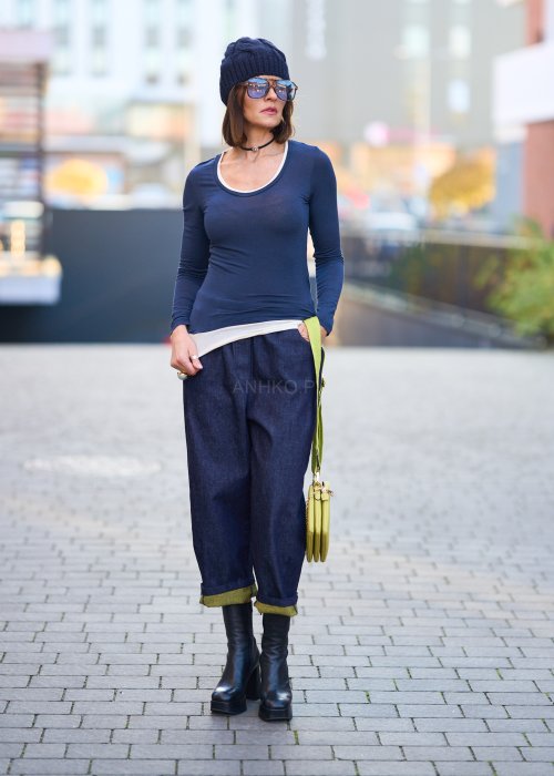 Luźne granatowe spodnie jeansowe z zielonymi detalami na kieszeni i podwiniętych nogawkach, stylizowane z dopasowaną bluzką i botkami na obcasie w miejskim looku.