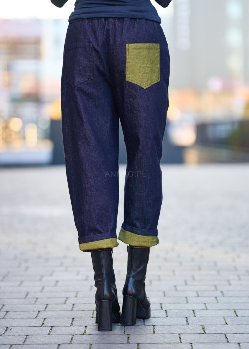 Luźne granatowe spodnie jeansowe z zielonymi detalami na kieszeni i podwiniętych nogawkach, stylizowane z dopasowaną bluzką i botkami na obcasie w miejskim looku.