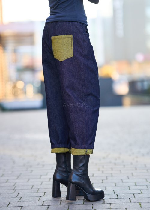 Luźne granatowe spodnie jeansowe z zielonymi detalami na kieszeni i podwiniętych nogawkach, stylizowane z dopasowaną bluzką i botkami na obcasie w miejskim looku.