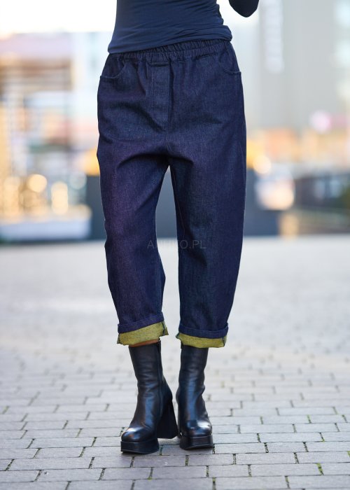 Luźne granatowe spodnie jeansowe z zielonymi detalami na kieszeni i podwiniętych nogawkach, stylizowane z dopasowaną bluzką i botkami na obcasie w miejskim looku.