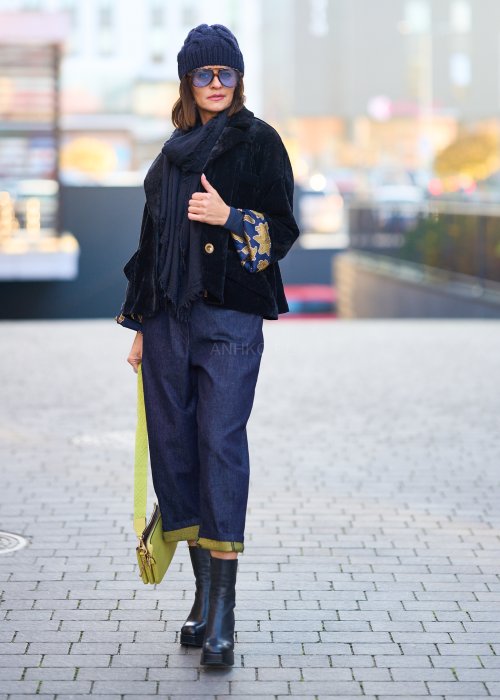 Luźne granatowe spodnie jeansowe z zielonymi detalami na kieszeni i podwiniętych nogawkach, stylizowane z dopasowaną bluzką i botkami na obcasie w miejskim looku.