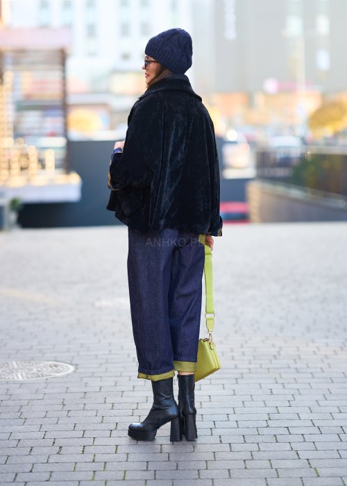 Luźne granatowe spodnie jeansowe z zielonymi detalami na kieszeni i podwiniętych nogawkach, stylizowane z dopasowaną bluzką i botkami na obcasie w miejskim looku.