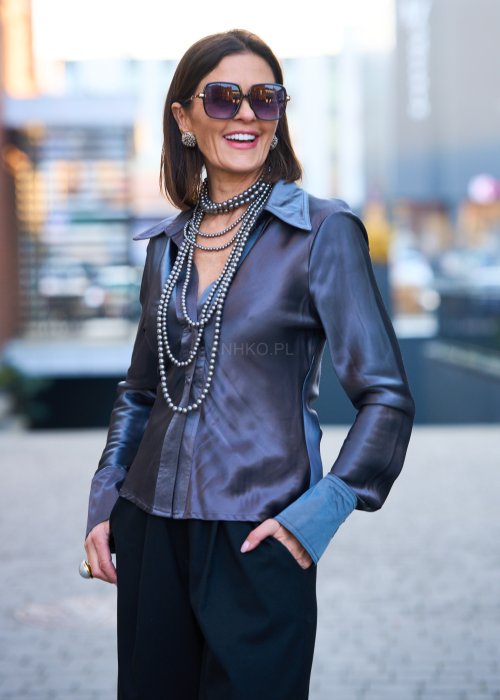 Elegancka bluzka koszulowa o dopasowanym, kobiecym kroju, wyraźnie modelującym talię. Wykonana z gładkiej, lejącej tkaniny o satynowym połysku