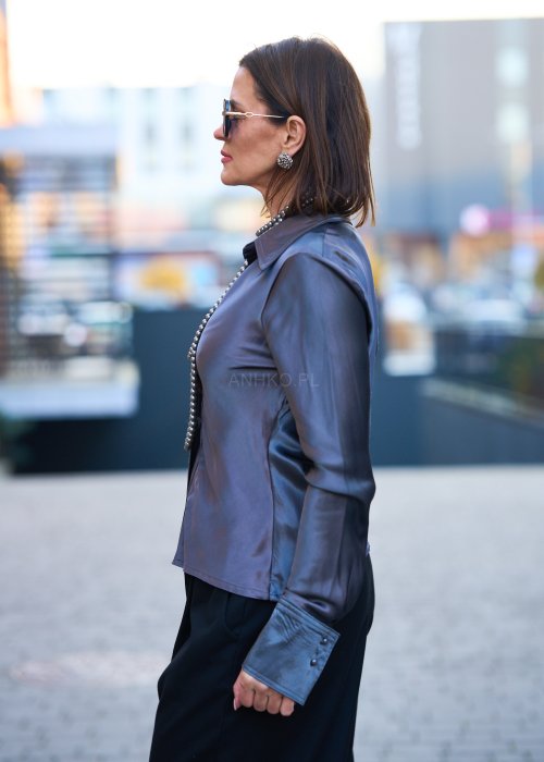 Elegancka bluzka koszulowa o dopasowanym, kobiecym kroju, wyraźnie modelującym talię. Wykonana z gładkiej, lejącej tkaniny o satynowym połysku