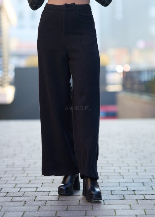 Czarne damskie spodnie z prostą, lekko rozszerzaną nogawką, gładkie, o klasycznym kroju, zestawione z czarnymi botkami na obcasie