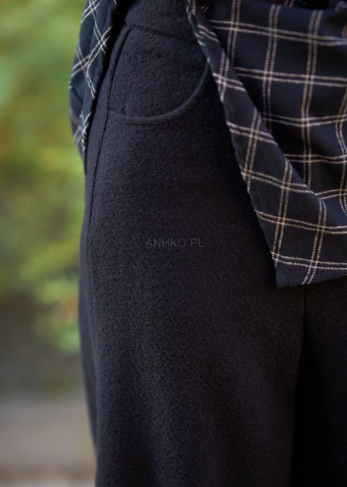 Czarne damskie spodnie z prostą, lekko rozszerzaną nogawką, gładkie, o klasycznym kroju, zestawione z czarnymi botkami na obcasie