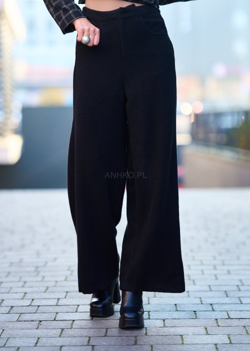 Czarne damskie spodnie z prostą, lekko rozszerzaną nogawką, gładkie, o klasycznym kroju, zestawione z czarnymi botkami na obcasie