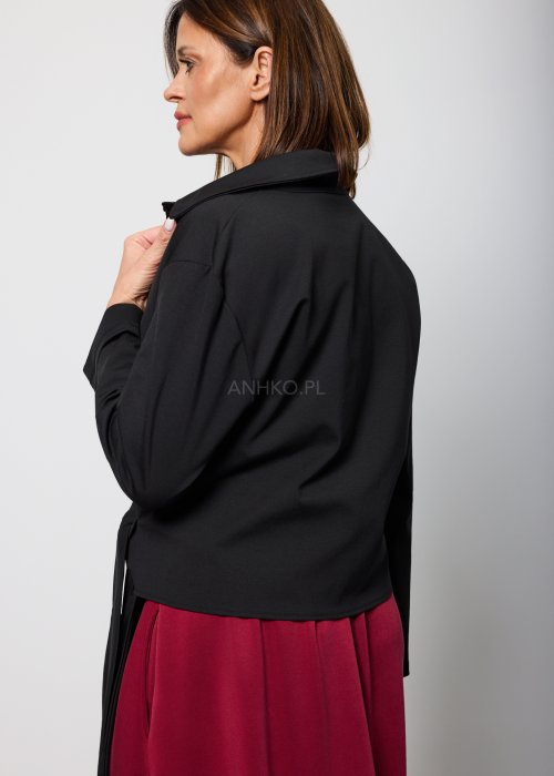 Czarna bluzka damska z asymetrycznym wiązaniem i klasycznym kołnierzem, o eleganckim fasonie. Stylizacja ze spódnicą w intensywnym kolorze w nowoczesnym wydaniu.